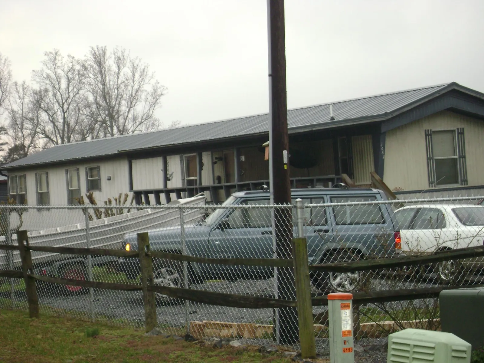 Dark metal roof on a long single story building behind a chain link fence in Hartland