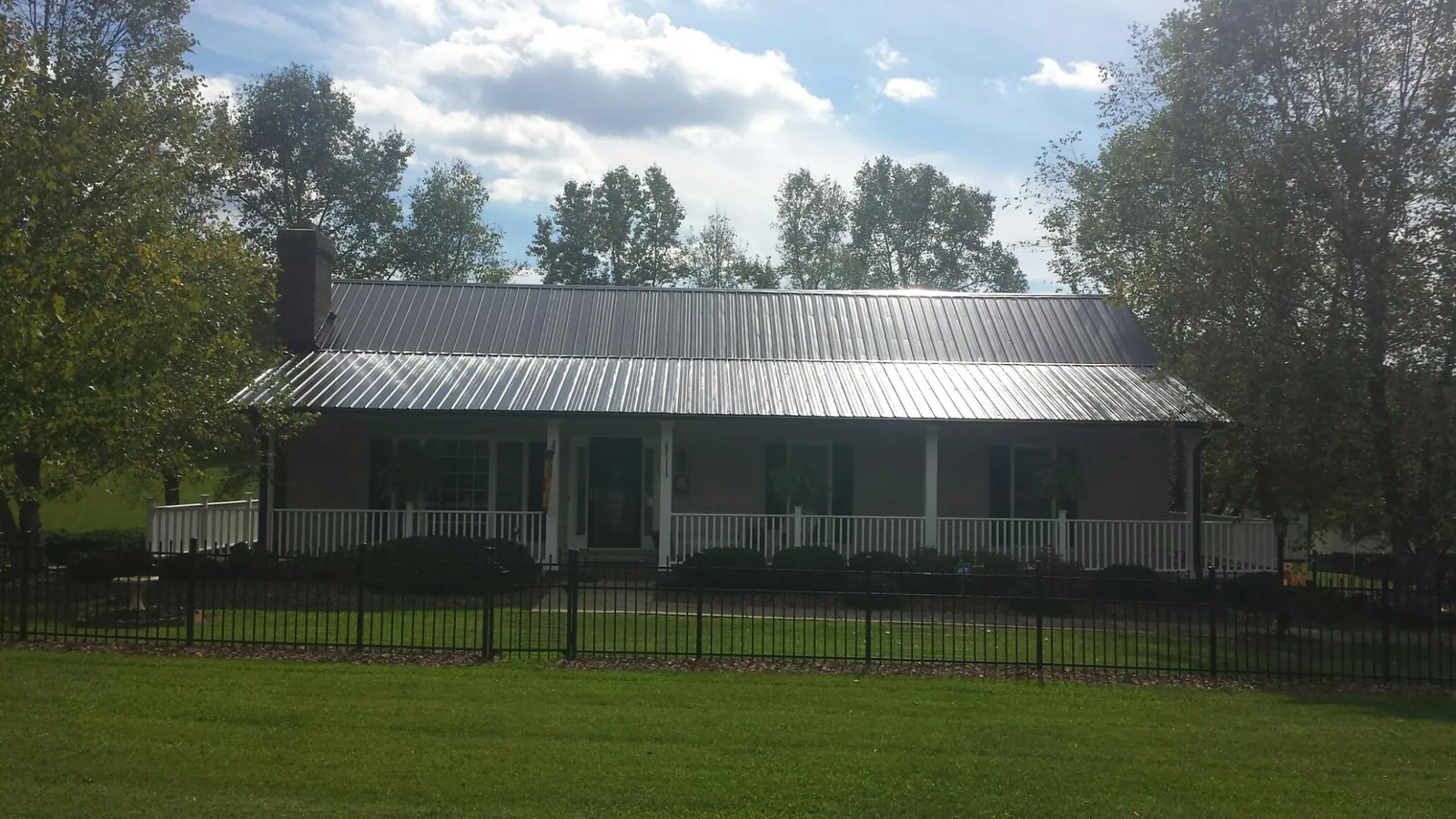 Gray metal roof on a brick ranch with a full width front porch — Gutter Guard Installation work by our crew in Hartland